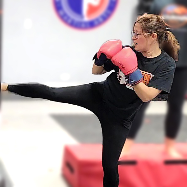 Adult DKFA kickboxing student practicing a side kick during class
