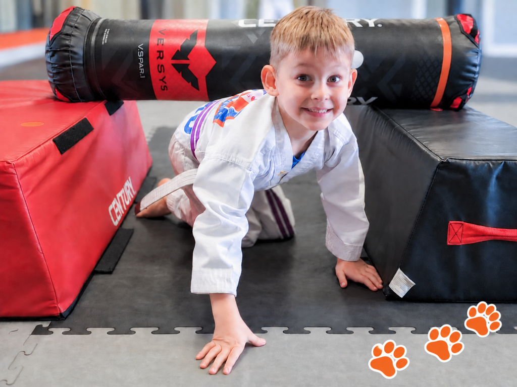 Smiling Tiger Tots student crawling through a padded obstacle at DK Fitness Arts